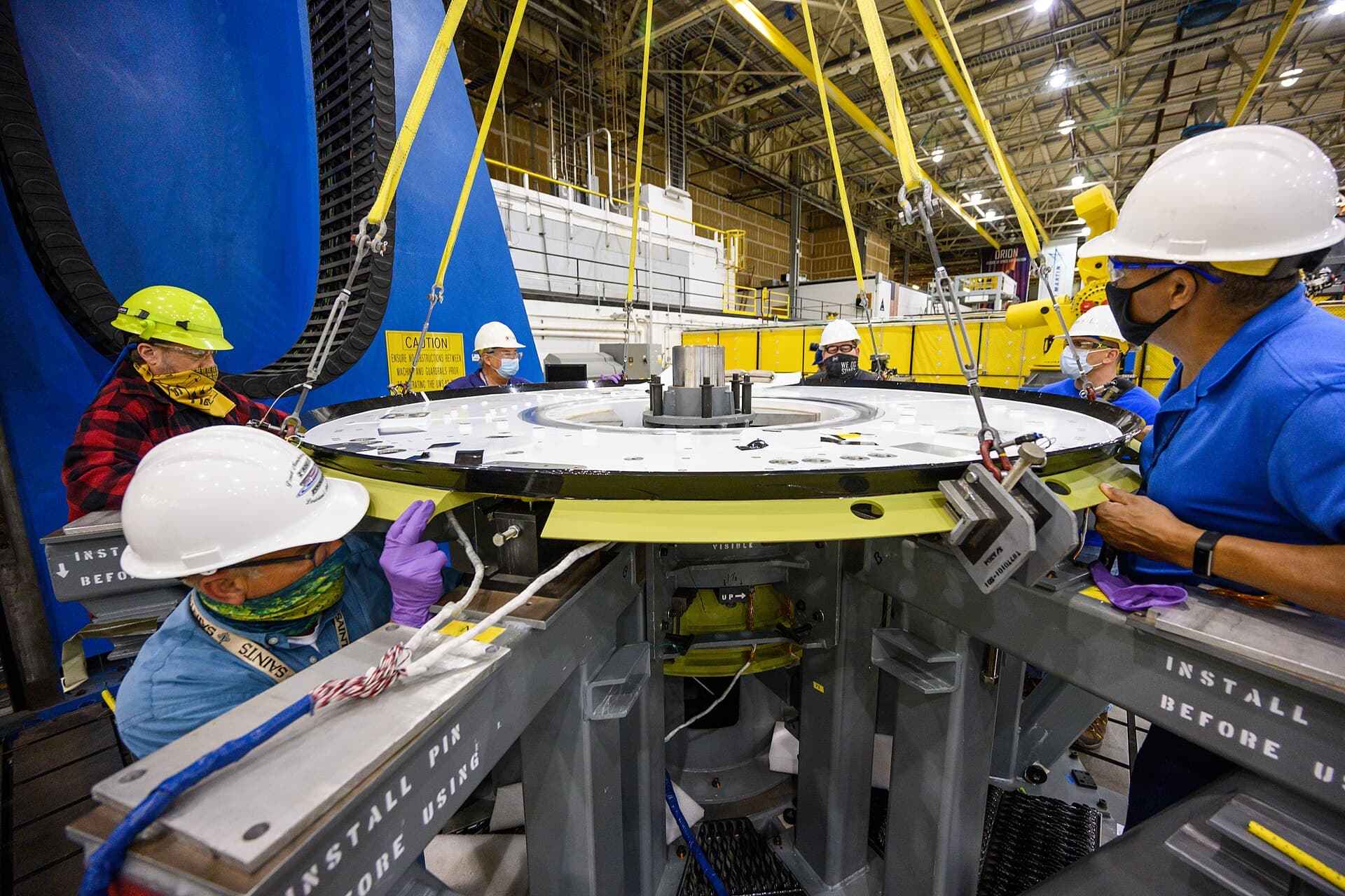 Engineers assembling a spacecraft structure in a clean room