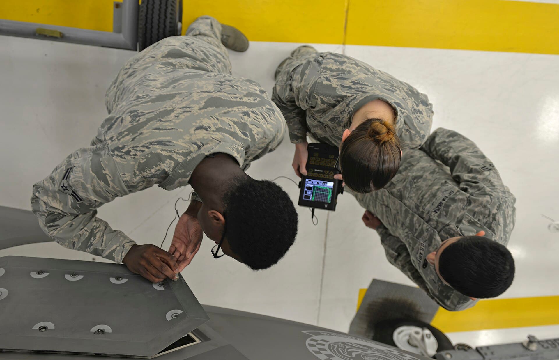 Technicians running a non-destructive inspection on an airframe panel